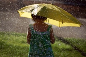 little girl holding a yellow umbrella under the rain