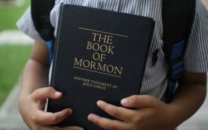 A young boy holding the Book of Mormon.