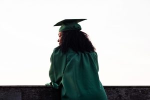 woman in graduation clothes looking outside